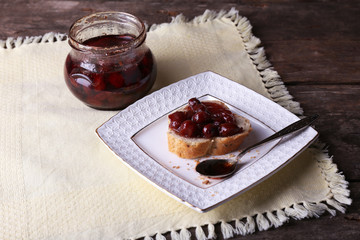 Fresh bread with jam on plate on table close up