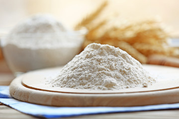 Fototapeta na wymiar Pile of flour on wooden cutting board and blurred background
