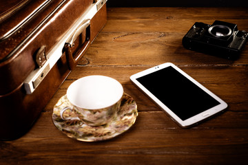 Suitcase and old camera, tablet, phone and a cup of coffee
