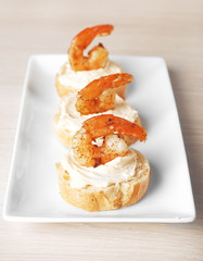 Appetizer canape with shrimp on plate on wooden background