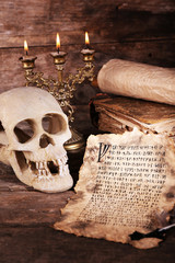 Still life with human skull, retro letter and candlelight on wooden table, closeup