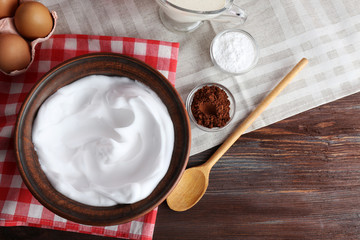 Whipped egg whites and other ingredients for cream on wooden table, top view