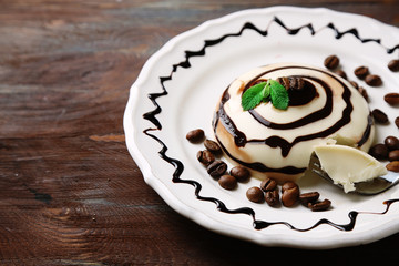 Tasty panna cotta dessert on plate, on wooden table