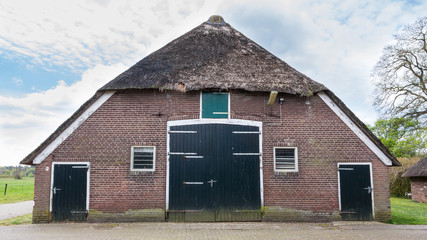 Fototapeta na wymiar Old farmhouse with reed roof and barn in the Netherlands