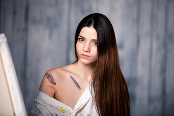 beautiful girl draws picture in the studio smeared with paint