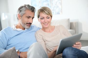 Middle-aged couple websurfing on internet with touchpad