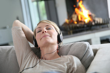 Woman listening to music by fireplace