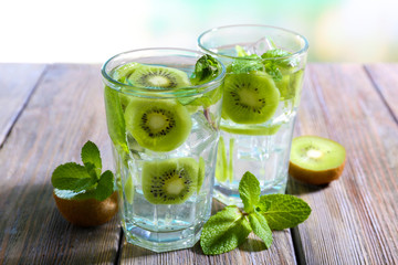Glasses of cocktails on wooden table on bright blurred background