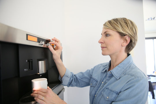 Middle-aged woman using expresso coffee machine