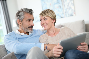 Middle-aged couple websurfing on internet with touchpad