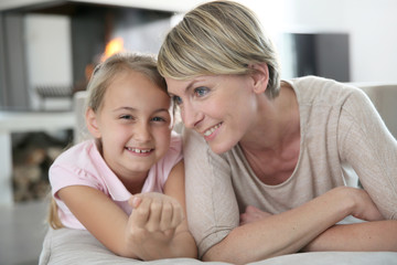 Portrait of mother and daughter laying in couch at home