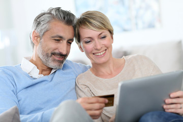 Cheerful mature couple e-shopping on internet