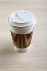 Paper cup of coffee on wooden background