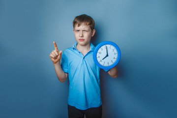 Boy teenager European appearance ten years holding a wall clock 