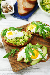 Tasty sandwiches with egg, avocado and vegetables on wooden background