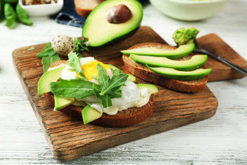 Tasty sandwiches with egg, avocado and vegetables on wooden background