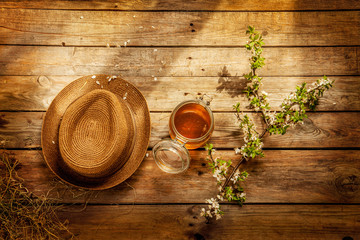 Country - jar of honey, gardener's hat and blooming tree branch on vintage rustic wood captured from above. 