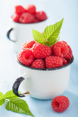 fresh raspberry in enamel cup over blue background