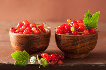 fresh redcurrant in cups over rustic wooden background