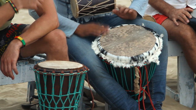 Unidentified man playing on drum at the beach