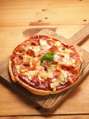Hawaiian pizza on wood plate