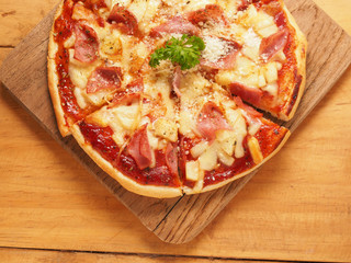 Hawaiian pizza on wood plate