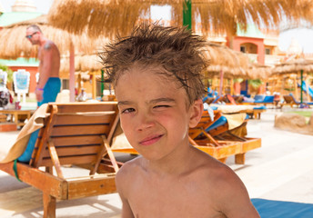 European boy with shaggy head after swimming in the water Park