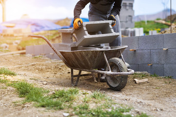 Bricklayer taking another brick from a wheelbarrow