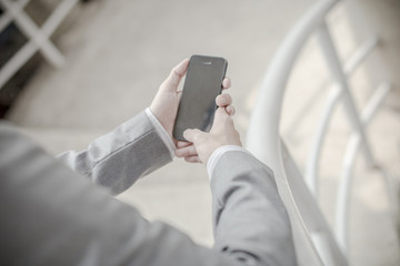 Young businessman using a phone sitting on the stairs