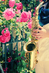 Saxophonist playing on saxophone on pink roses background