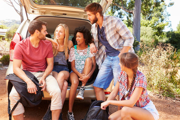Group Of Friends On Trip Sitting In Trunk Of Car