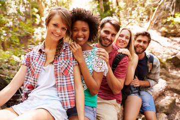 Group Of Friends On Walk Balancing On Tree Trunk In Forest