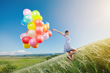 Beautiful woman with colorful balloons outside.