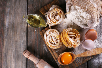 Raw homemade pasta and ingredients for pasta on wooden background