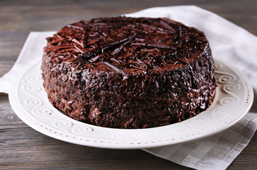 Delicious chocolate cake on plate with napkin on wooden table background