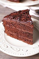 Delicious chocolate cake in white plate on wooden table background, closeup