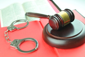 Law concept with gavel and handcuffs against red book