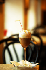 Glass of coffee with cream on table in cafe