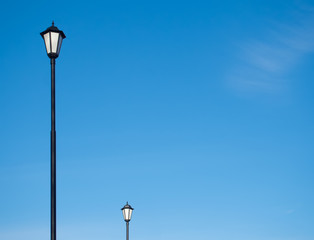Fototapeta na wymiar Street lamps silhouette against the blue sky