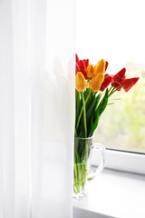 Bouquet of fresh tulips on windowsill background