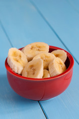 Sliced banana in pot over a blue table.