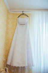 White Wedding dress hanging on a shoulders, before ceremony. 