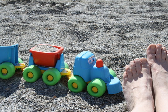 Italy, Liguria, Loano - Feet on rocky beach, high angle view