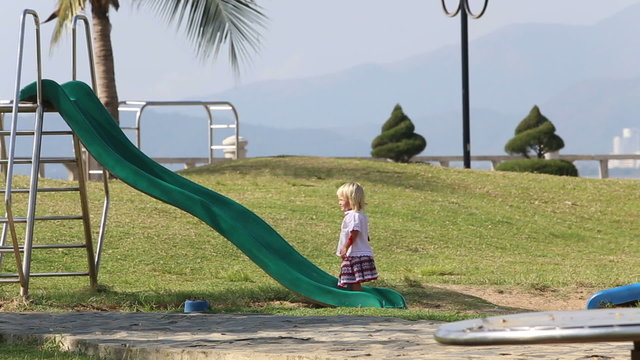 blonde girl in Ukrainian blouse comes to slide to climb	
