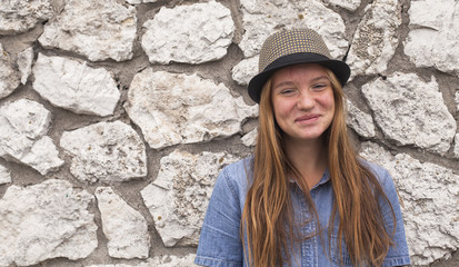 Funny young girl near a stone wall.