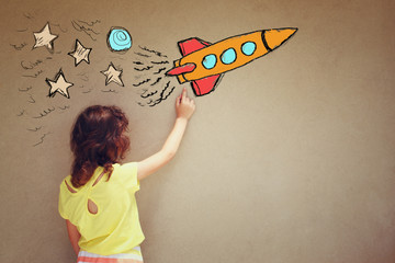 back view of cute kid (girl) imagine space rocket