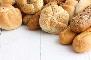 Bread rolls and baguettes on rustic white painted wood.