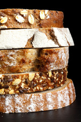 Mixed slices of health breads stacked. On black.