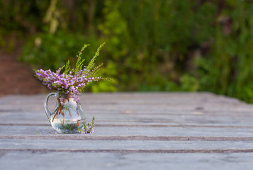 a bouquet of Heather in a glass jar on the boards