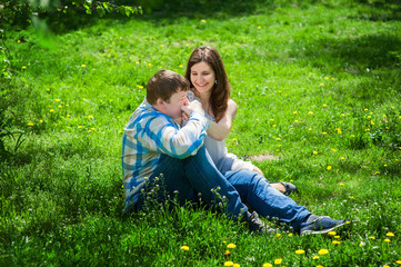 Fototapeta premium Man with a woman sitting on the grass and he kisses her hand